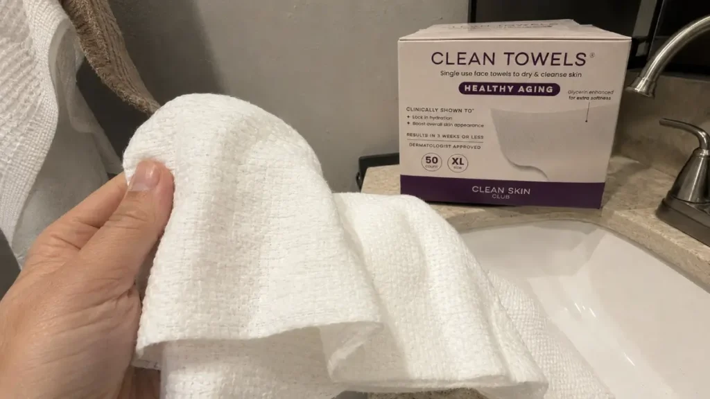 A hand holding one dry facial towel to show its thickness and soft texture