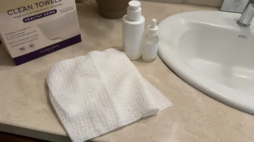 A dry facial towel placed beside a moisturizer and serum on a bathroom counter