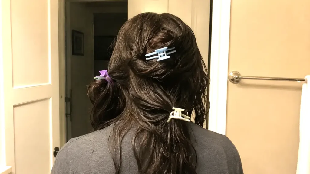Thick, coarse, and damp hair divided into sections with hair clips before styling.